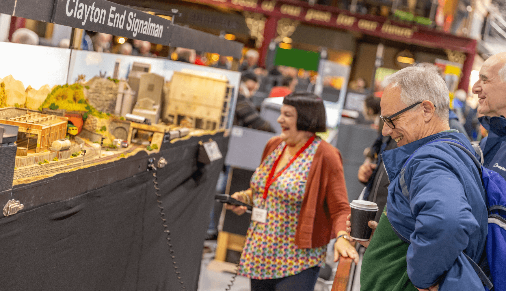 A small group of people standing in front of a model railway layout